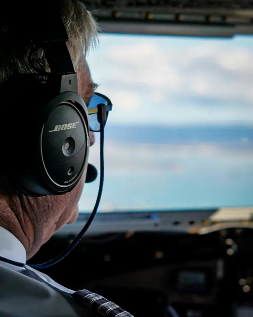Pilot wearing a headset viewed from behind inside an aircraft cockpit