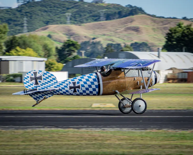 Vintage biplane rolling along a runway with the background blurred by motion
