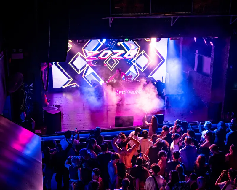 Elevated view of a stage with pink smoke and an audience