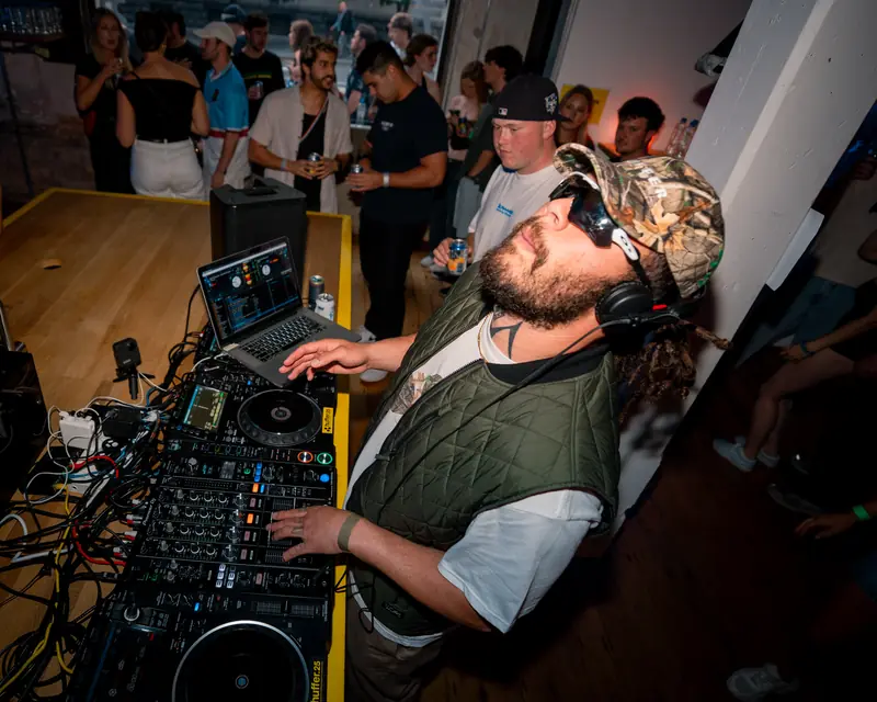 DJ wearing a cap at the mixer in a crowded venue