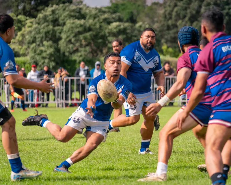 Rugby league player diving forward with the ball as defenders close in