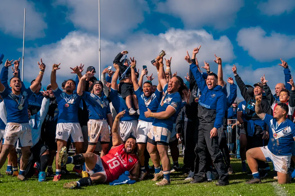 Rugby league team celebrating together beneath the goal posts