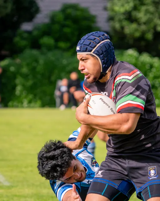 Rugby league player carrying the ball through a tackle