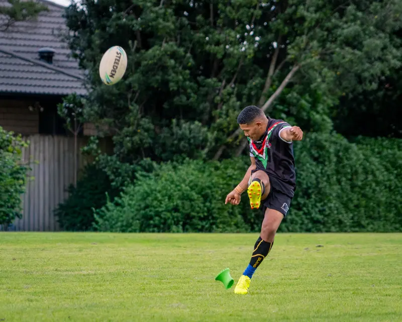 Rugby league player kicking the ball on an open field